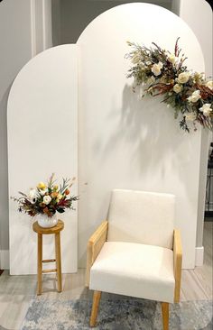 a white chair sitting on top of a rug next to a vase filled with flowers