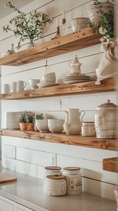 the shelves in this kitchen are filled with white dishes and cups, along with some greenery