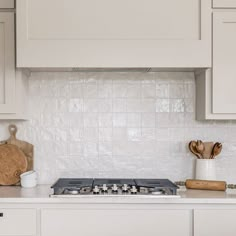 a stove top oven sitting inside of a kitchen next to wooden utensils and cutting board