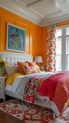 a bedroom with orange walls and colorful bedding in front of a large window that has flowers on it