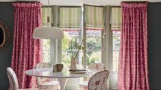 a dining room with pink curtains and chairs