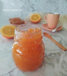 a jar filled with liquid sitting on top of a table next to sliced oranges