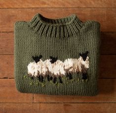 a green sweater with three sheep on it