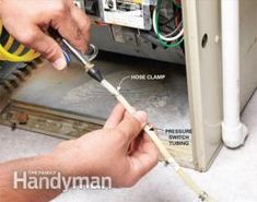 a man is working on an air conditioner and fixing the wires that are plugged in