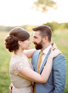 a bride and groom embracing each other in an open field