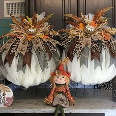 two pumpkins decorated with feathers and fall decorations