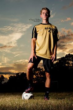 a young man standing on top of a field next to a soccer ball in the grass