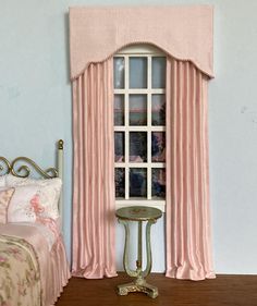 a doll house bedroom with pink curtains and bed in the foreground, window to outside