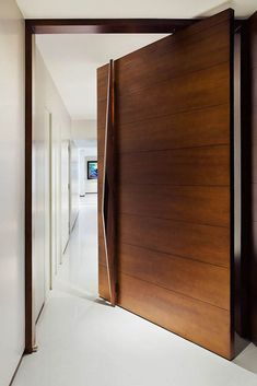 an open wooden door leading into a hallway with white walls and flooring on both sides