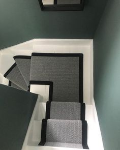 the stairs are lined with black and gray carpeting in this room, which is painted green