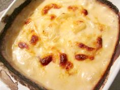 a casserole dish with cheese and bacon in it sitting on a white plate