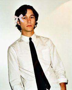 a young man wearing a white shirt and black tie with a pink bow on his head