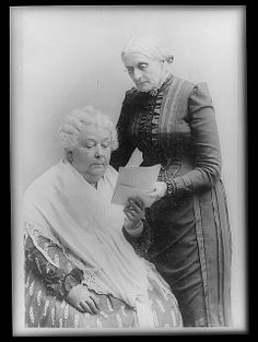 an old photo of two women sitting next to each other holding papers in their hands