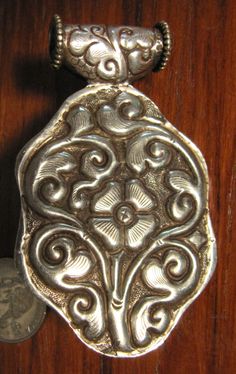 This Tibetian Silver Pendant has a wonderful Orange Coral center dome cab with reddish Amber spots and small turquoise inlay on bezel. The front and back has a wonderfully carved silver floral design. It is 2 7/8 inch long with bezel. 1 3/4 inch wide at face and about 5/8 inch deep. This can be worn on a chain or incorporated into a beaded necklace. Ornate Antique Silver Carved Jewelry, Carved Silver Medallion Jewelry, Ornate Carved Medallion Jewelry, Traditional Carved Silver Jewelry, Traditional Polished Medallion Jewelry, Traditional Medallion Jewelry With Polished Finish, Traditional Carved Medallion Jewelry, Orange Coral, Resin Beads