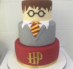 a harry potter birthday cake with glasses and a tie on the top is red, yellow and gray