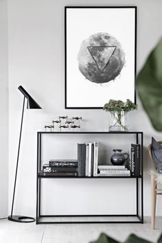 a black and white photo hanging on the wall above a bookshelf with plants