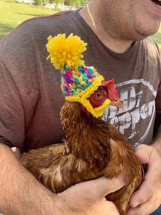 a man holding a chicken wearing a colorful hat