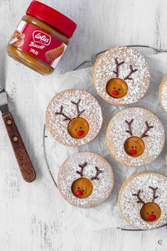 some frosted cupcakes with reindeer faces on them next to a jar of peanut butter