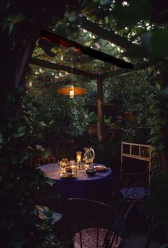 an outdoor dining area with blue table cloths and chairs, surrounded by greenery