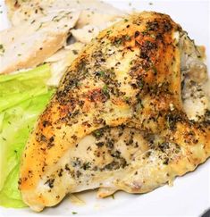 a white plate topped with chicken, lettuce and broccoli covered in seasoning