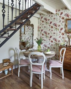 a dining room table with four chairs under a stair case