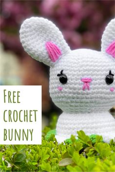 a crocheted bunny sitting in the middle of some green bushes with pink ears