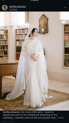 a woman in a white wedding dress and veil posing for a photo with bookshelves behind her