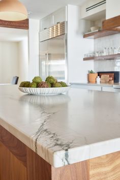 a bowl of broccoli sitting on top of a marble countertop in a kitchen