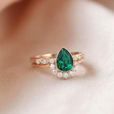 a close up of a ring with a green stone and diamonds on the side,