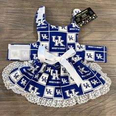 a dress made out of blue and white fabric with the letter h on it, sitting on top of a wooden floor