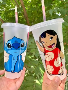 two people holding up plastic cups with cartoon characters on them