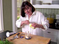 a woman is pouring something into a glass on the counter in front of a window