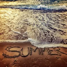 the word summer written in the sand at the beach with waves coming up on it