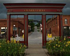 the entrance to clarksville is surrounded by sunflowers and other flowers in front of brick buildings