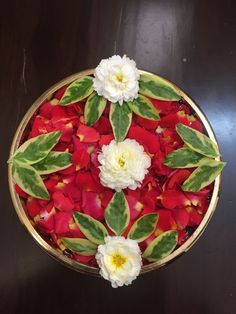 a bowl filled with flowers and leaves on top of a table