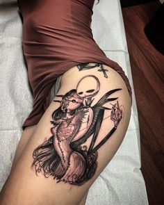 a woman's thigh with a tattoo on it and a skeleton holding a knife