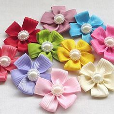 six different colored hair bows with pearls on the center and one is white, pink, blue, green, yellow