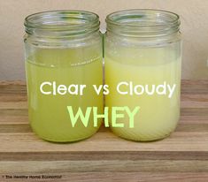 two jars filled with yellow liquid sitting on top of a wooden table next to each other