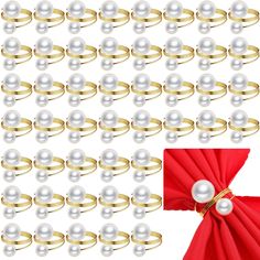 white pearls and gold rings are arranged in rows on a red table cloth with a red bow