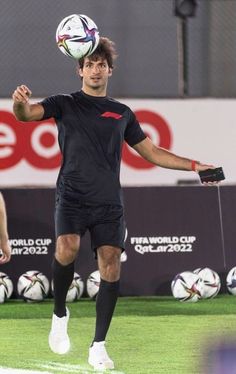 a man in black shirt kicking a soccer ball on top of his head with other men behind him