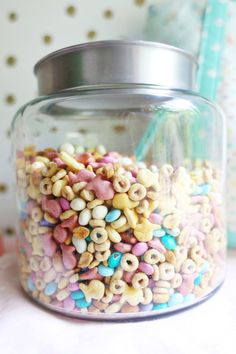 a glass jar filled with cereal sprinkles sitting on top of a table