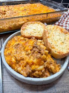 a bowl filled with food next to bread and a casserole dish on a table