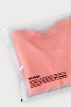 a pink t - shirt in a plastic bag on a white surface with the words pangaia printed on it