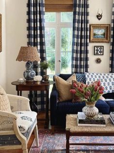 a living room filled with furniture next to a window covered in blue and white curtains