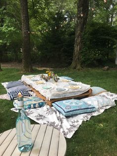 a picnic table set up in the woods with plates and napkins on top of it