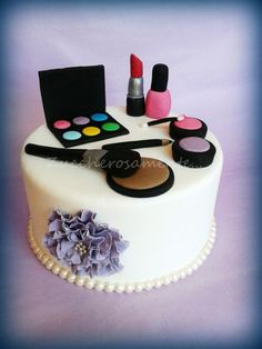 a cake decorated with makeup and cosmetics on top of a purple tableclothed surface