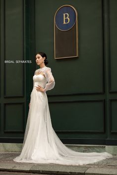 a woman in a white wedding dress standing on the sidewalk with her hands on her hips