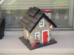 a small toy house sitting on top of a window sill