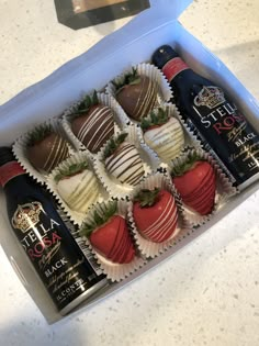 six chocolate covered strawberries and two bottles of wine in a white box on a counter