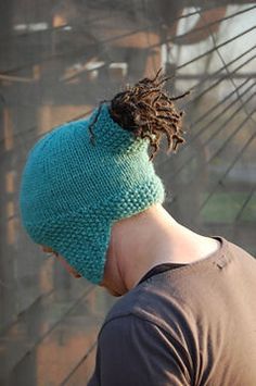 a man with dreadlocks wearing a blue knitted hat and looking down at the ground